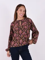Blusa estampada con flores en tonos rosa, negro y verde. Tiene cuello redondo con abertura en forma de lágrima y mangas largas con puños elásticos.