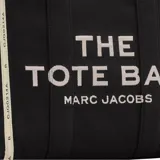 Bolso tipo tote de gran tamaño, confeccionado en lona de algodón y poliéster color negro. Presenta el logo estampado en blanco en el frente y bordes reforzados con detalles de texto. Cuenta con doble asa superior para llevar al hombro.