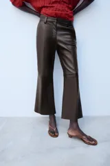 Pantalón de tiro medio confeccionado en 100% piel de color marrón, con diseño flare y costuras decorativas.