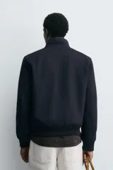 Cazadora de corte regular confeccionada en tejido de lana y cashmere. Presenta cuello subido, cierre frontal con cremallera, bolsillos de plastrón con solapa en la parte frontal y acabados en rib en puños y cintura.