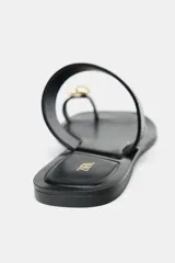 Sandalia plana negra con tira ancha en el empeine y tira para el dedo con detalle de abalorio metalizado. Suela cuadrada.