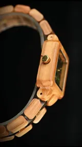 Reloj de pulsera con caja cuadrada de madera de olivo y esfera verde con marcadores minimalistas y agujas doradas. La malla es de madera de olivo con eslabones centrales metálicos en tono dorado.