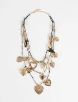 Collar de tres capas compuesto por cordones negros finos y múltiples dijes metálicos en tono dorado con formas de corazones variados, incluyendo corazones lisos, texturizados y con detalles calados.