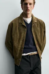 Sobrecamisa relaxed fit de piel con acabado en ante de color verde militar, con cuello solapa, manga larga con puño abotonado, bolsillos de vivo en la cadera y cierre frontal con botones.