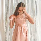 Vestido corto color salmón, con escote cuadrado, mangas cortas abullonadas y falda con vuelo. El top y las mangas son plisados y elastizados.