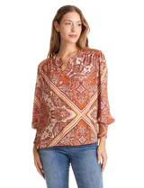 Blusa de gasa estampada con diseño de arabescos en tonos tierra. Presenta cuello a la base con escote en V, hombros con detalle de punto smock y mangas 3/4 con puños anchos también en punto smock.