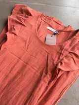 Vestido largo color coral de tusor, con escote redondo, mangas cortas con volados y aberturas laterales.