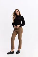 Blusa negra de algodón con textura fruncida en todo el cuerpo, cuello alto y puños con volados.