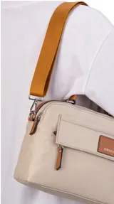 Bandolera de nylon color tostado de formato compacto y estructurado, con asa de mano superior y correa larga desmontable y regulable. Cuenta con cierre principal, bolsillo frontal con cierre bajo solapa y bolsillo trasero con cierre.