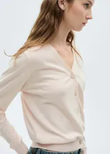 Cardigan de punto fino en color rosa claro, con cuello en pico, cierre frontal de botones y manga larga con puños acanalados.