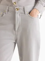 Pantalón Cuore de gabardina en tono gris cemento, con silueta ajustada en la cintura y pierna semi oxford con tajos laterales en el ruedo. Incluye botón metálico dorado con forma de corazón en el frente y pasadores.