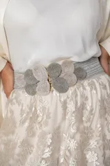 Cinturón ancho elástico de color gris, con diseño trenzado y hebilla ornamental compuesta por piezas circulares de hilo entrelazado en tonos grises.