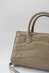 Cartera mediana color verde oliva, de cuero con diseño acolchado con pespuntes ondulados. Tiene doble asa corta y correa larga desmontable.