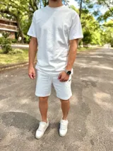 Conjunto deportivo blanco compuesto por una remera de manga corta de corte holgado y un short con cordón ajustable en la cintura.