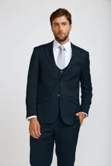 Traje de tres piezas compuesto por saco, chaleco y pantalón de corte slim fit en color azul oscuro. El saco presenta solapas clásicas y cierre de dos botones, el chaleco cuenta con cierre frontal de botones y el pantalón es de corte recto y entallado.