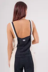 Musculosa de lino con diseño bicolor en negro y beige, escote en V y bordados decorativos en el frente. Presenta un corte holgado con tajos laterales y breteles regulables en la espalda.