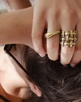 Anillo de diseño abierto con estructura de rejilla entrelazada, elaborado artesanalmente en metal con acabado plateado.