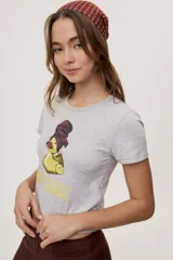 Remera blanca de manga corta, con estampa frontal de un pato de hule con turbante y labios pintados, acompañada de la frase "In all else fails, denial".