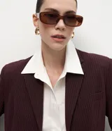 Blazer sastre de corte recto y estructura firme, color bordó con estampado de rayas de tiza. Presenta cuello con solapas definidas, cierre frontal con dos botones y mangas largas.