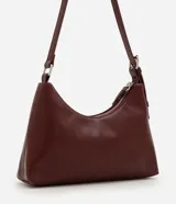 Cartera tipo baguette de tamaño pequeño en cuero sintético color bordó, con correa ajustable y cierre de cremallera metálica con herrajes en níquel.