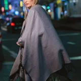 Poncho de acrílico color gris con flecos en el borde inferior.