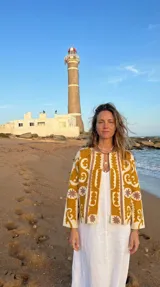 Chaqueta corta de algodón rústico color crudo con bordados en tonos mostaza, ocre y tabaco, inspirada en los textiles Suzani. Tiene un corte abierto y estructurado.