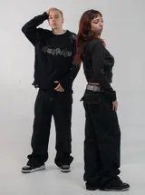 Pantalón de jean negro de corte regular y tiro bajo, con costuras decorativas visibles en las piernas y diseño de paneles.