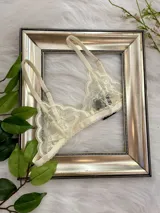 Bralette de encaje color champagne, con copas triangulares, breteles regulables y cierre de gancho en la espalda.