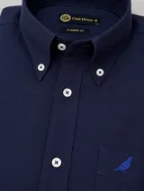 Camisa de algodón twill color blanco de corte clásico, con cuello button-down, bolsillo en el pecho con detalle bordado y botones en tono contrastante con costuras en cruz.