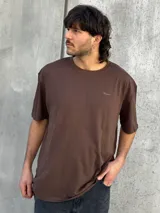 Remera marrón de corte amplio con estampado en la espalda con la palabra 'Perception' y otras frases en color dorado.