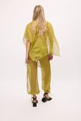 Pantalón ancho de seda color amarillo, estilo parachute o globo, con talle alto y cordones ajustables en los tobillos.