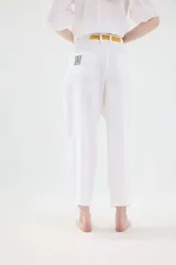 Pantalón de lino marrón de tiro medio, con calce holgado y diseño de piernas amplias. Cuenta con bolsillos traseros, trabillas para cinto y un pin bordado en contraste.
