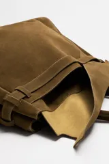 Bolso de mano extragrande color marrón oscuro, estilo tote o satchel, fabricado en piel. Presenta dos asas de mano y un detalle de cinta ajustable con cierre de solapa en la parte frontal superior.