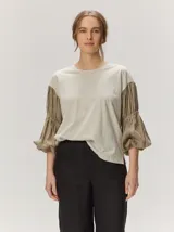 Remera blanca con cuerpo de algodón liso y mangas abullonadas semitransparentes con textura de lunares.