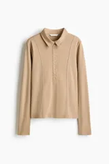 Remera polo de manga larga confeccionada en punto de algodón, con cuello clásico, tapeta frontal con botones y costuras moldeadoras en el frente.