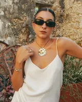 Collar artesanal con dije central de metal con textura orgánica irregular que evoca una ostra. El dije está montado sobre un cordón de algodón natural, permitiendo un uso versátil y regulable.