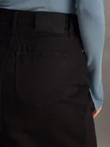 Falda midi de denim color negro, de tiro alto, corte recto y abertura frontal.