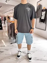 Remera oversize negra de manga corta con estampado tipográfico blanco en la espalda.