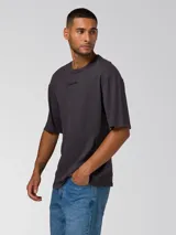 Remera de manga corta color gris oscuro con efecto lavado, cuello redondo y logo bordado en el pecho. Cuenta con un parche tejido en la manga.