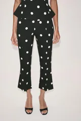 Mono largo de escote recto sin tirantes, con peplum en la cintura, perneras acampanadas y estampado de lunares.