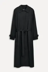 Trench negro largo con cuello solapa, manga larga con trabilla y botón, bolsillos delanteros, cinturón ajustable con lazadas, abertura en la espalda y cierre frontal con botones ocultos por solapa.