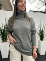 Polerón de cuello alto en color verde seco, con diseño de tejido de punto y detalle de trenza vertical en el frente. Presenta mangas largas con puños acanalados y un corte holgado.