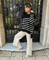 Sweater de punto con diseño a rayas horizontales en blanco y negro, cuello redondo y corte holgado con tajos laterales en el ruedo.