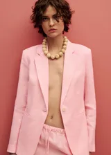 Chaqueta de lino color rosado, con diseño recto, cuello con solapas de muesca y cierre frontal de un botón. Cuenta con mangas largas con puños abotonados, dos bolsillos de ribete delanteros y abertura posterior en el bajo.