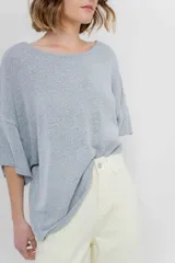 Sweater oversize de tejido liviano color blanco roto, con textura semi traslúcida, escote redondo y mangas amplias estilo murciélago.