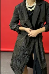 Tapado largo de tela tornasolada que combina tonos gris, marrón y azul. Tiene corte recto, mangas amplias y forro completo.