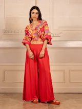 Pantalón palazzo negro de lino con cintura elástica, bolsillos laterales y cinturón con hebilla circular.