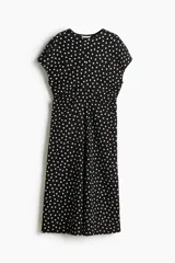 Vestido midi en punto texturizado de color negro con estampado de lunares blancos, escote redondo y manga corta. Cuenta con cintura entallada.