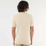 Remera tipo polo de manga corta confeccionada en tejido de punto con textura acanalada, color beige, con cuello camisero y cartera de tres botones carey.