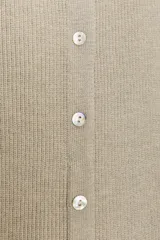 Top de punto acanalado en color beige, sin mangas y con cuello redondo. Presenta un cierre frontal con botones pequeños y un bajo con acabado en peplum que aporta volumen.